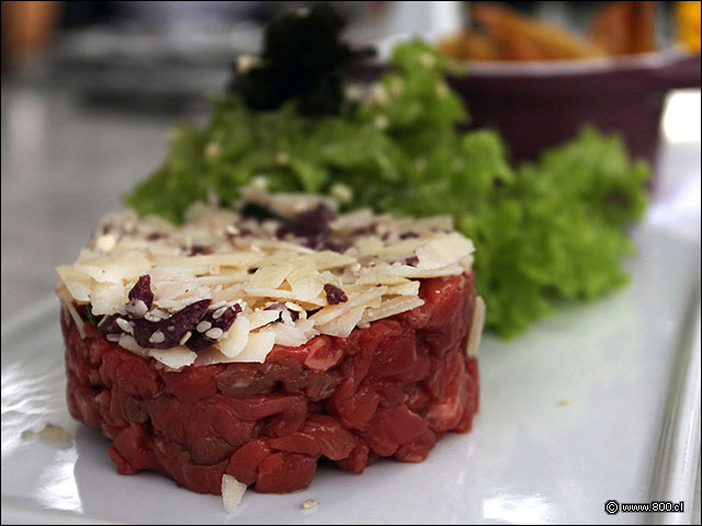 Carne picada a cuchillo con una capa de aceitunas moradas y queso parmesano en el Trtaro de aCstillo Forestal - Castillo Forestal