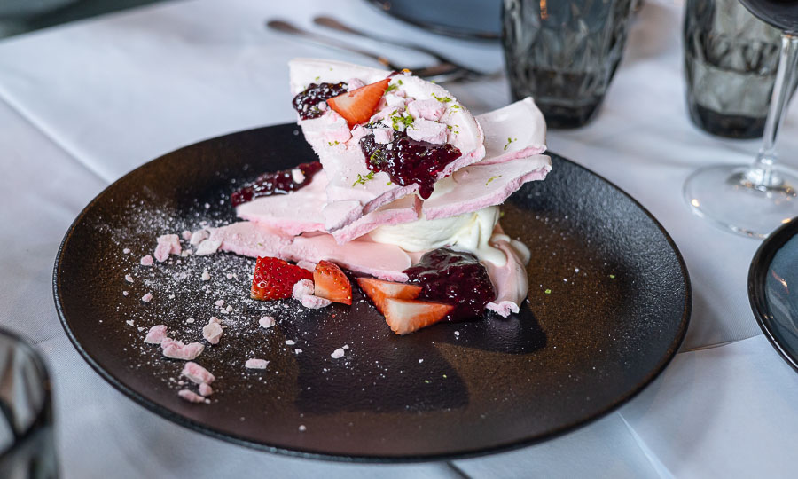 Postre rosado de merengue y frutillas