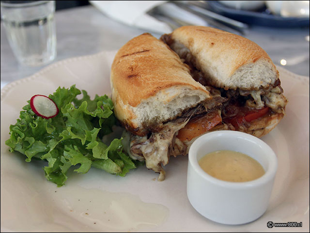 Sabroso sndwich de mechada con queso fundido y tomate servido en marraqueta