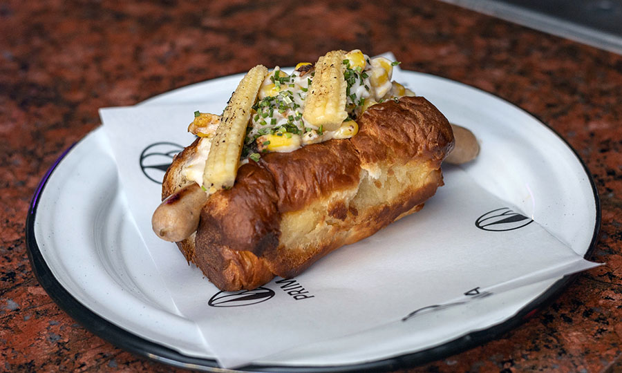 Completo de choclo a la crema con queso en longaniza de pollo - Prima Bar - CV Galería