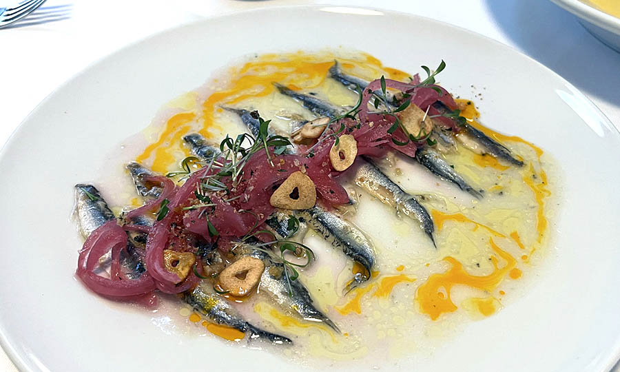 Boquerones en conserva con cebollas encurtidas, chips de ajo y pangrattato