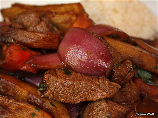 Detalle de Lomo Saltado, dados de filete, gajos de tomate y cebolla morada salteados con soya junto a papas fritas acompaado por arroz blanco - El Aj Seco del Inca - Ex El Chaln