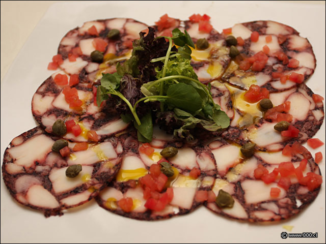 Carpaccio de Pulpo, finos cortes de pulpo aderezados con Alcaparras, Tomate y Oliva